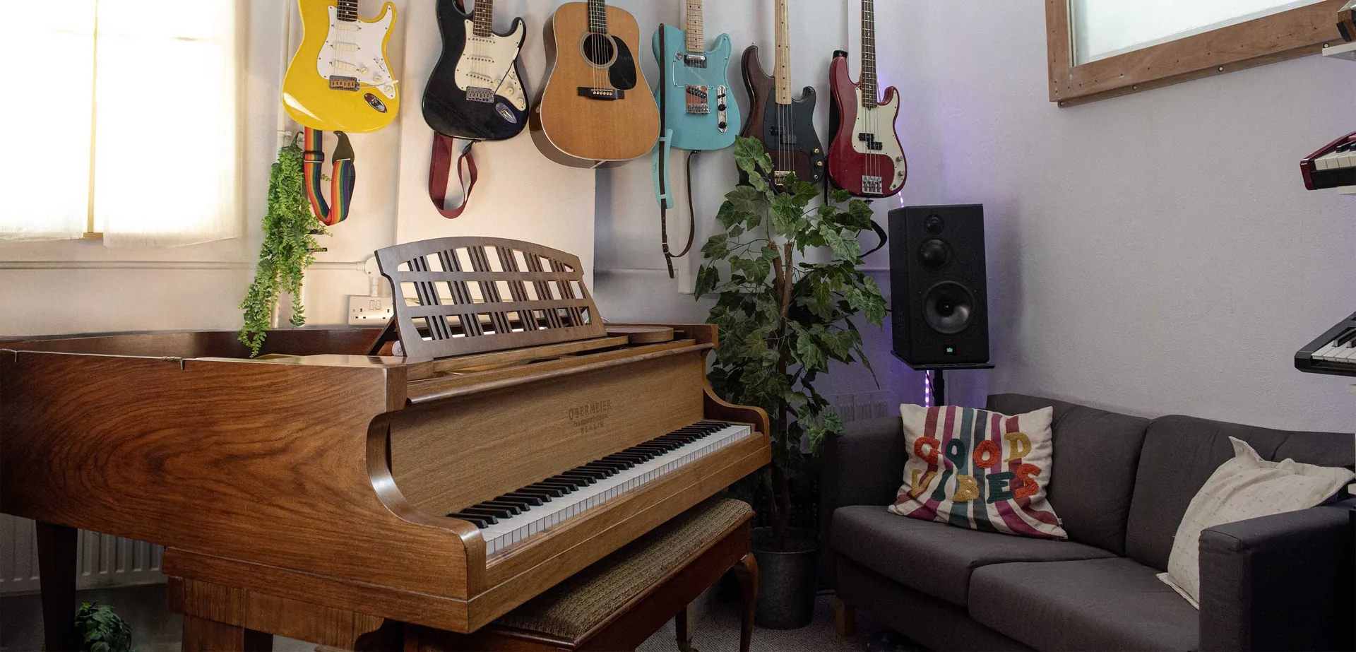 The writing room: grand piano and a wall of guitars and basses